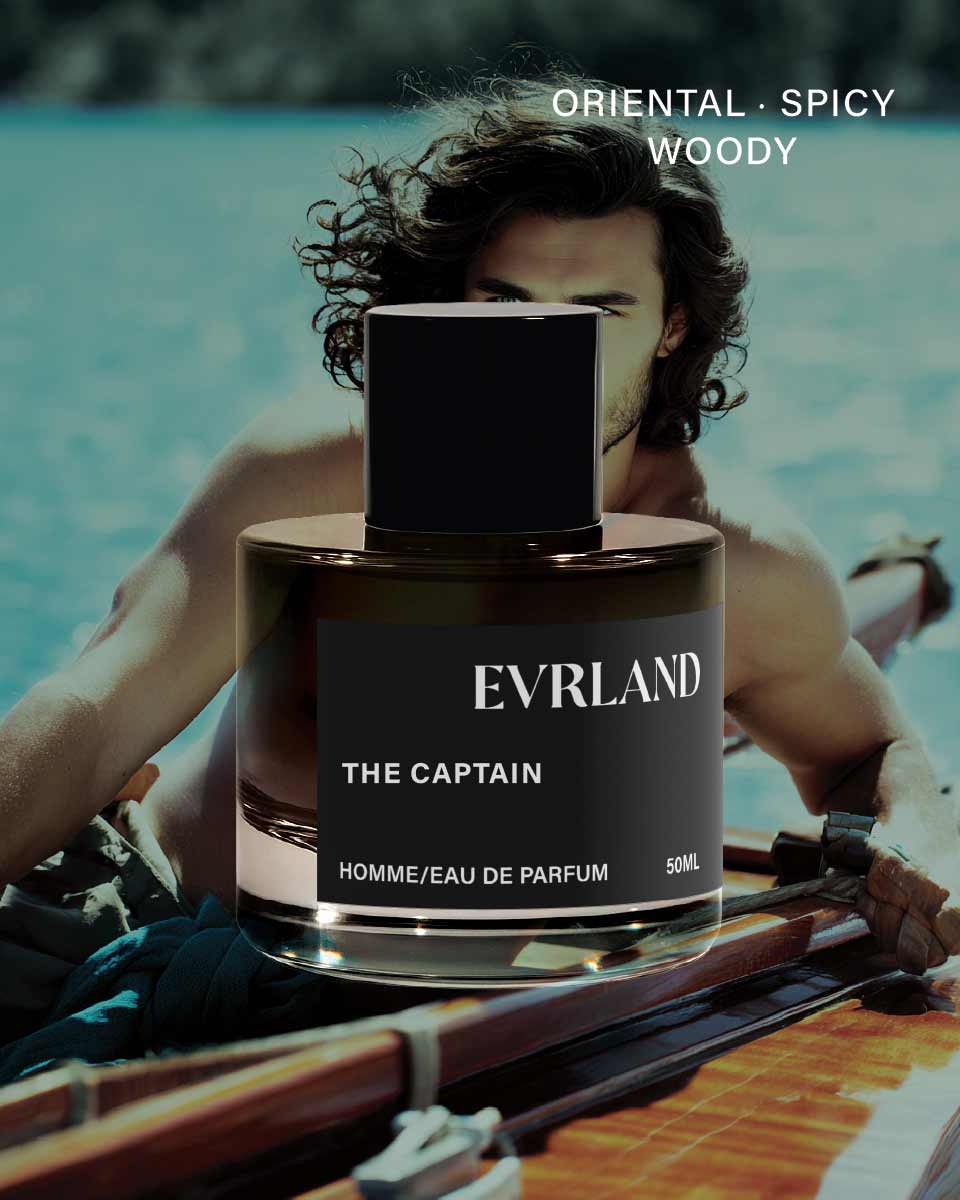 Perfume bottle labeled 'Evrland The Captain' with a person in the background by a body of water.